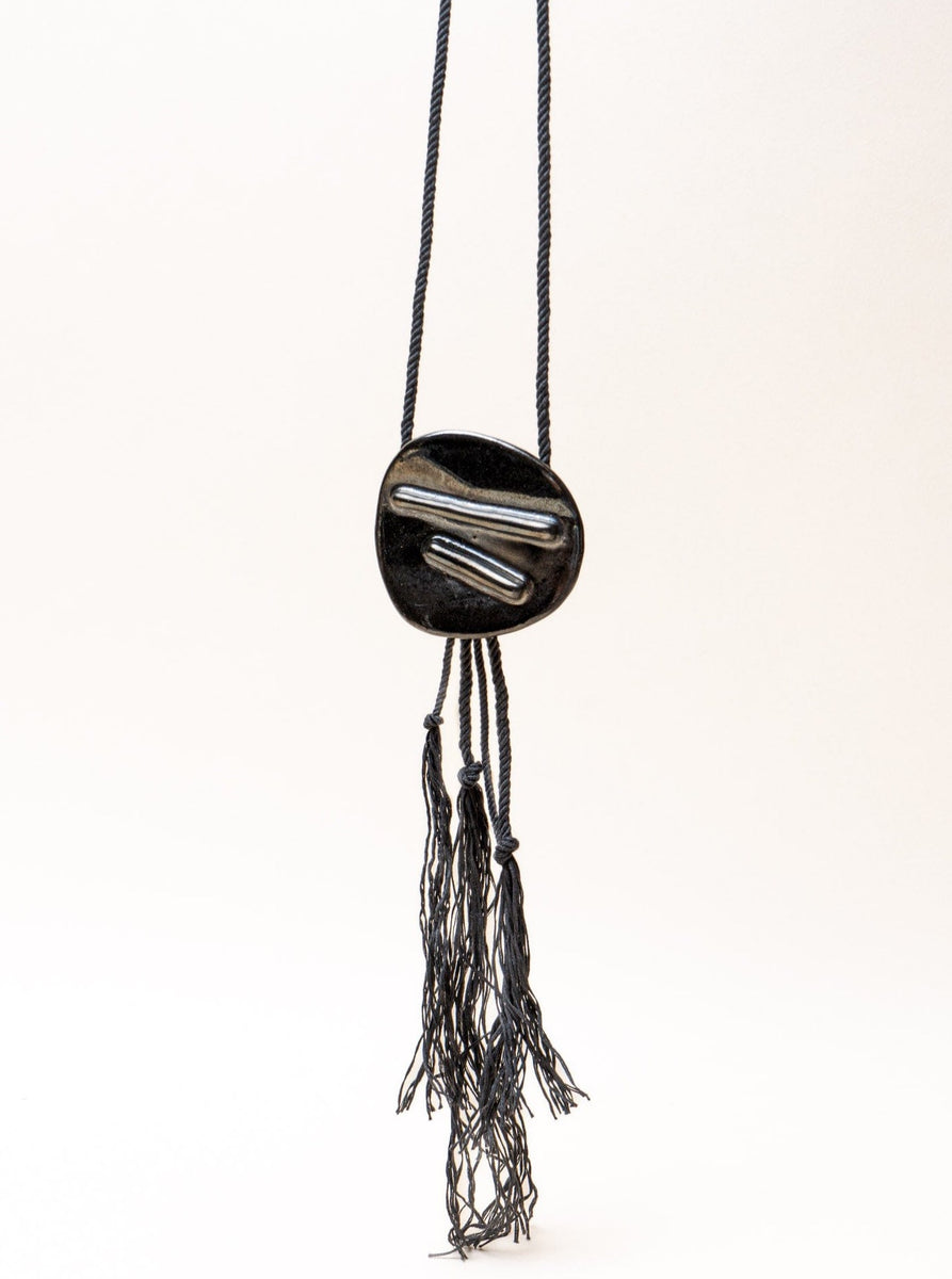 A handmade Edena Necklace with tassels hanging from it.