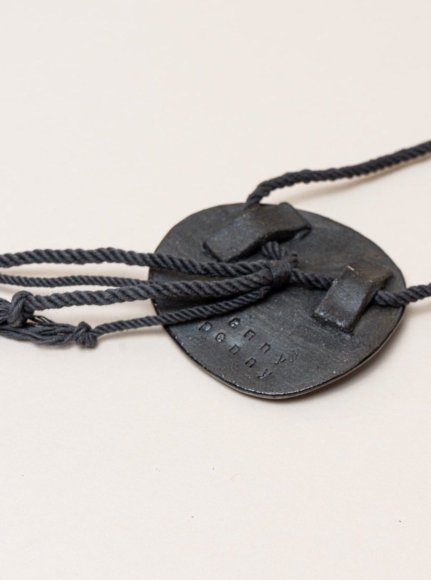 A handmade Edena Necklace crafted by an artist, with a rope attached to it.