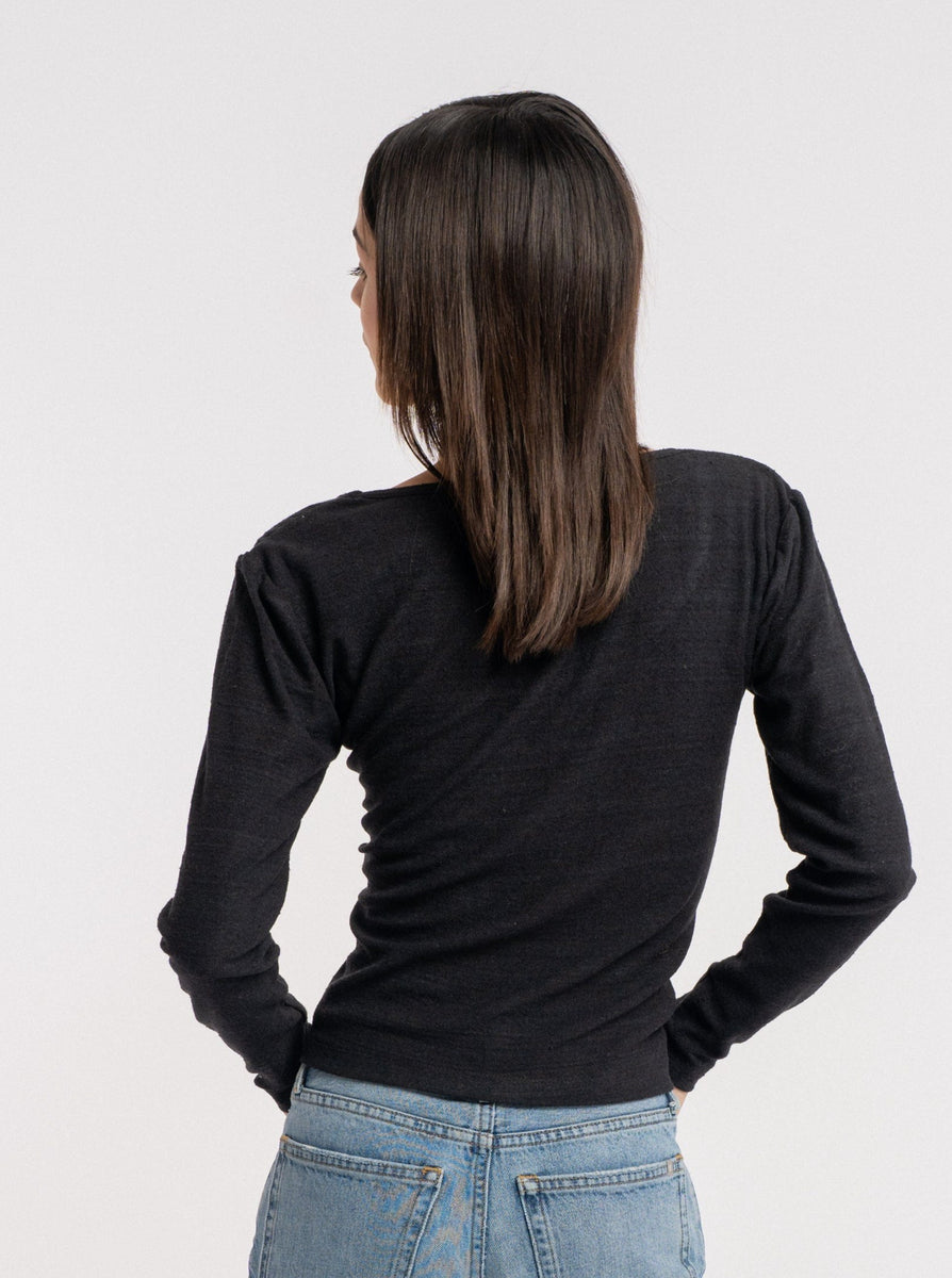 The back view of a woman wearing jeans and a black sweater, showcasing sustainability in her choice of clothing with an eco-friendly silk noil material, highlighted by the Scoop Neck Tee - Black.