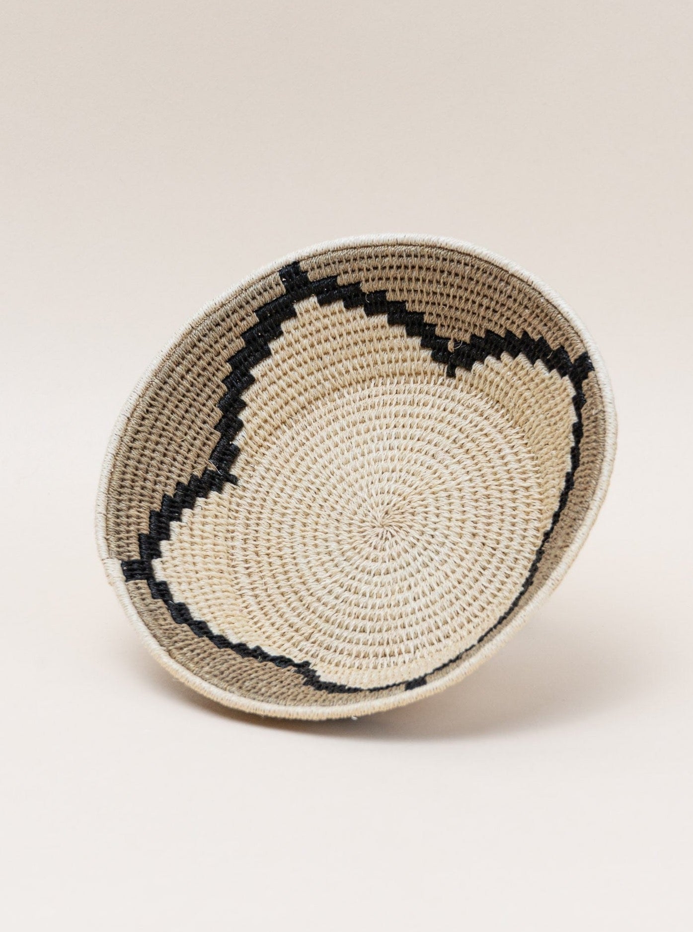 A Handmade Sisal Catchall Basket, showcasing Swazi weaving techniques, on a white surface.