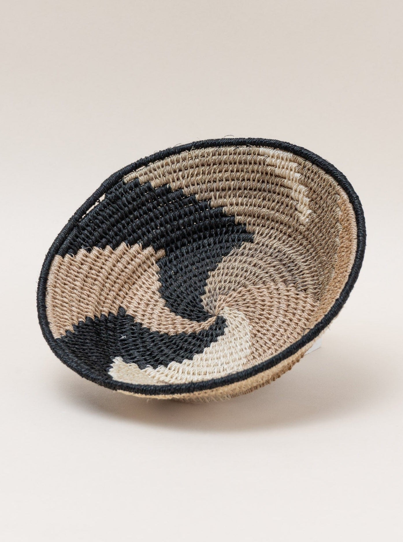 A Handmade Sisal Catchall Basket on a white surface, showcasing Swazi weaving techniques.