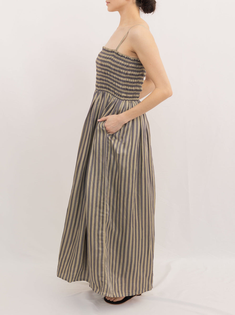 Woman wearing an Urban Stripe spaghetti strap maxi dress with a gathered waist, standing sideways against a white background.
