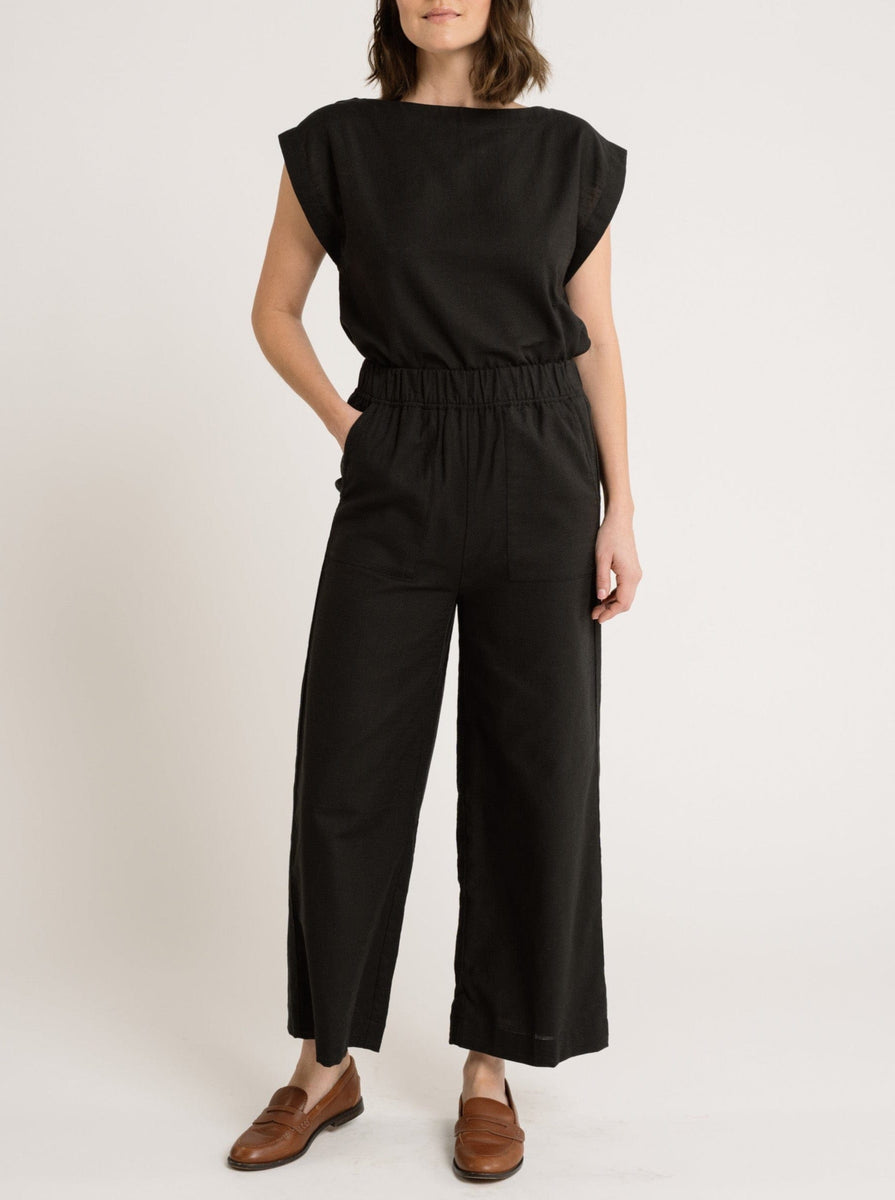 A woman wearing the Everyday Crop Pant - Black Cotton jumpsuit with a high-waisted, sleeveless top.